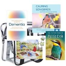 Clear backpack with bird themed puzzle and books and a book about taking care of someone with Dementia